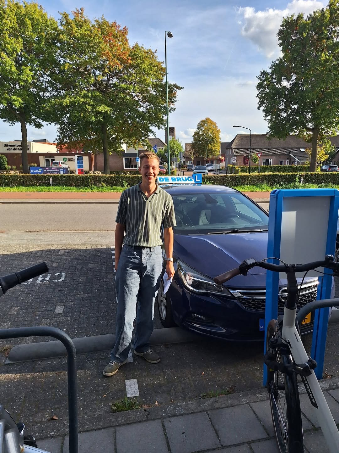 Geslaagde leerling in het dorp naast de lesauto van Autorijschool De Brug