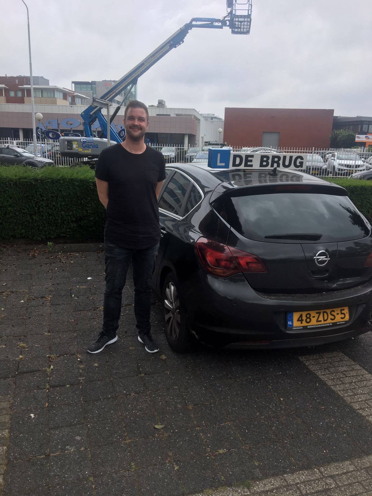 Geslaagde leerling staat trots naast de lesauto van Autorijschool De Brug